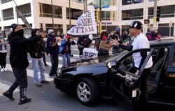 A motorist pleads to let him drive through on a street next to the Hennepin County Government Center as protesters held vehicles at bay until they honked their horns, March 29, 2021, in Minneapolis.
