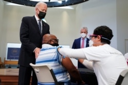 U.S. President Joe Biden puts his hand on a man's shoulder during a visit to a coronavirus disease vaccination site at Virginia Theological Seminary in Alexandria, Virginia, April 6, 2021.