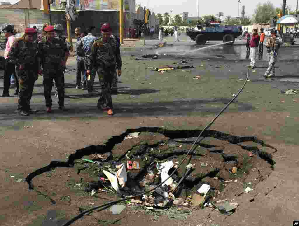Security forces and civilians inspect a crater caused by a car bomb explosion in the commercial area of New Baghdad, Iraq, Aug. 26, 2014.