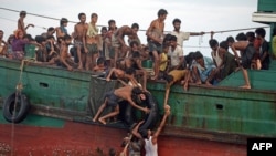 Rohingya migrants pass food supplies dropped by a Thai army helicopter to others aboard a boat drifting in Thai waters off the southern island of Koh Lipe in the Andaman Sea, May 14, 2015. 