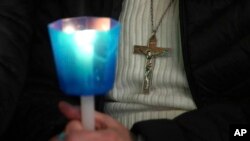 Yon dam kenbe yon bouji pandan lap lapriye ansanm ak Kadinal Victor Manuel Fernandez pou amelyorasyon sante Pap Franswa nan Vatikan an, 28 Fevriye 2025. 