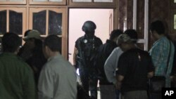 FILE - Indonesian police officers of Special Detachment 88 anti-terror unit search for evidence following a raid on a house used as a hideout by suspected militants' in Mojokerto, East Java, Indonesia, Dec. 19, 2015.