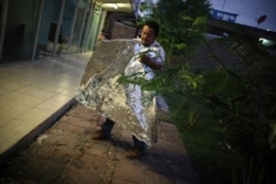 A Honduran migrant, who was returned from the U.S. the previous day, folds the emergency blanket U.S. immigration officials gave him as he camps with other migrants outside a Mexican immigration office in Matamoros, Mexico, Aug. 4, 2019.