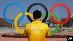 FILE - A volunteer photographs a set of Olympic Rings at Olympic Park in Rio de Janeiro, Brazil, July 29, 2016.