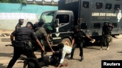 FILE - Police officers pull a journalist during an anti-government protest in Lagos, August 5, 2019. 