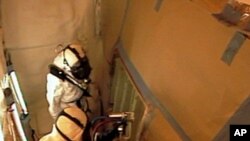 Technicians spray foam insulation on a section of repaired stringers on space shuttle Discovery's external fuel tank