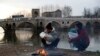 Migrants hold their babies as they try to warm themselves next to a river in Edirne, Turkey, near Turkish-Greek border, March 4, 2020.