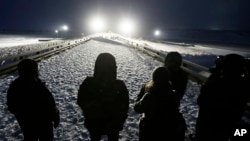 Military veterans stand on a bridge across from police protecting the Dakota Access oil pipeline site in Cannon Ball, N.D., Dec. 1, 2016.