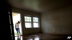 FILE - In this Aug. 31, 2017 file photo, Alejandra Castillo takes a break from carrying water-soaked items out of her family's home after flood waters receded in Houston. Experts say Harvey’s filthy floodwaters pose significant dangers to human safety and the environment that will remain even after levels drop far enough that southeastern Texas residents no longer fear for their lives.