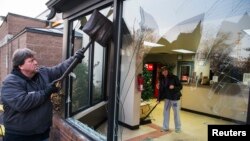 Business owner Jim Bolin and Mary Sue Patterson work to clean up their vandalized car care center following a second night of protests in Ferguson, Missouri, Nov. 26, 2014. 