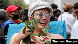 Musician and activist Chaiamorn 'Ammy' Kaewwiboonpan, 32, receives roses as he arrives to report himself on royal insult charges, at the attorney general's office in Bangkok, Thailand, Feb. 17, 2021. 
