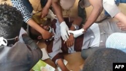 An image grab taken from AFP TV on Jan. 17, 2019, shows medics looking after an injured man after police fired tear gas at hundreds of protesters marching towards the presidential palace in the capital Khartoum demanding the resignation of the Sudanese president.