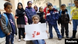 FILE - Syrian refugee Tesnim Faydo, 8, shows her drawing of a mother crying for her wounded daughter, as she is surrounded by her friends in Yayladagi refugee camp in Hatay province near the Turkish-Syrian border, Turkey, Dec. 16, 2015.