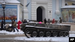 People pass by the entrance to St. Michael Cathedral, with a damaged Russian military vehicle in the foreground, in central Kyiv, Ukraine, Dec. 12, 2022. 