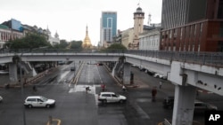 Vehicles make their ways as pedestrians cross a road with Sule pagoda seen the in background in downtown Yangon, Myanmar, July 19, 2021.