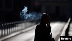 A man smokes a cigarette as he walks early morning in Frankfurt, Germany, Sept. 8, 2020.