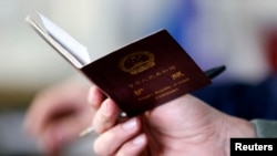 FILE - A police officer checks the passport of a Chinese immigrant in Prato, Italy, Dec. 9, 2013. 