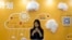 A woman uses her smartphone near a booth promoting cloud services during the Global Mobile Internet Conference in Beijing, China, April 29, 2016.