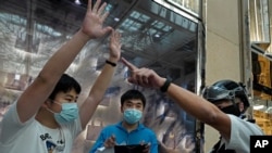 FILE - Protesters, center and left, are detained by a police officer in a shopping mall in during a pro-democracy protest against Beijing's national security law, in Hong Kong, July 21, 2020.