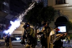 A riot police officer shoots a tear gas to disperse anti-government demonstrators protesting on Christmas Eve in Hong Kong, Dec. 24, 2019.