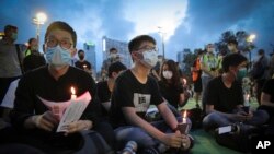 Hong Kong democracy activist Joshua Wong, center, holds a candle as he joins others for a vigil to remember the victims of the 1989 Tiananmen Square Massacre at Victoria Park in Causeway Bay, Hong Kong, June 4,2020. 