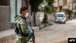 FILE - A member of the Kurdish Internal Security Forces of Asayesh stands guard on a deserted street in Syria's northeastern city of Hasakah.
