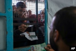 FILE - Palestinians line up to receive aid distributed by UNRWA, the U.N. agency helping Palestinian refugees, in Nusairat refugee camp, Gaza, Nov. 5, 2024.