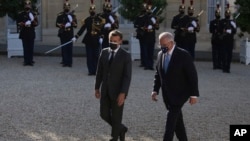 FILE - French President Emmanuel Macron, left, welcomes Australia's Prime Minister Scott Morrison before a working dinner in Paris, June 15, 2021. 