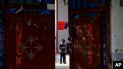 资料图：新疆和田的一名维吾尔小孩独自在家中院子里玩耍 （美联社 2018年9月20日）