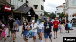 Para pengunjung pusat belanja Disney Springs di Lake Buena Vista, Florida, mengenakan masker wajah saat dibukanya kembali secara bertahap Walt Disney World setelah beberapa bulan tutup akibat pandemi Covid-19) AS 11 Juli 2020. REUTERS / Octavio Jones
