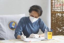 FILE - Daw Aung San Suu Kyi, Myanmar's de facto leader, fills out a ballot in her country's election in Naypyitaw, Oct. 29, 2020.