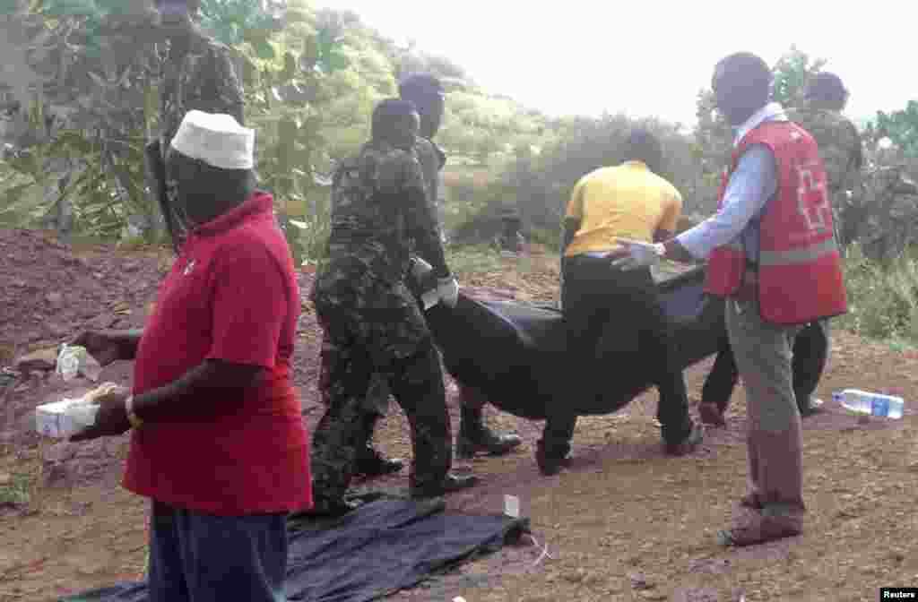 Kenyan military personnel and Red Cross volunteers carry bodies of people killed at a quarry in a village in Korome, outside the border town of Mandera, Kenya, Dec. 2, 2014.