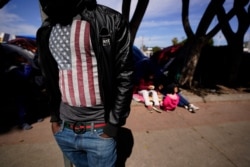 A migrant asylum seeker from Haiti waits at a makeshift camp of migrants at the border port of entry leading to the United States, March 17, 2021, in Tijuana, Mexico.