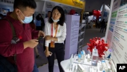 Seorang pengunjung mengenakan masker memperhatikan model virus corona untuk vaksin COVID-19 yang dipamerkan oleh perusahaan farmasi China Sinopharm di China International Fair for Trade in Services (CIFTIS) di Beijing, Sabtu, 5 September 2020.