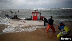 Fishermen pull a boat ashore at Angeiras beach near Matosinhos, Portugal, Feb. 12, 2018. 