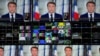 French President Emmanuel Macron is seen on screens as he delivers his televised New Year's address to the nation from the Elysee Palace in Paris on Dec. 31, 2024.