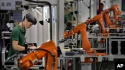 FILE - A man works amid orange robot arms at Rapoo Technology factory in southern Chinese industrial boomtown of Shenzhen. The country's trade with North Korea has slowed for the second consecutive year. 