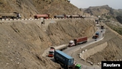 Trucks, stuck for days in Pakistan due to border conflict, travel toward the border post at Torkham, Pakistan June 18, 2016.