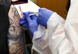 En esta foto del 27 de julio del 2020, la enfermera Kathe Olsmtead inyecta a un voluntario durante los estudios de una vacuna para el coronavirus en Binghamton, Nueva York.