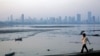 FILE - A man walks along a wall overlooking the central Mumbai financial district skyline.