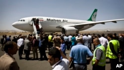 FILE - Yemeni airport security and transportation officials greet a plane from the Iranian private airline, Mahan Air after it lands at the international airport in Sana'a, Yemen.
