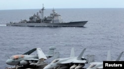 FILE - U.S fighter jets on standby at the upper deck of a USS George Washington aircraft carrier while the USS Cowpens passes by, in the South China Sea, 170 nautical miles from Manila.
