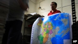 FILE - A worker holds a new officially approved map of China that includes the islands and maritime area that Beijing claims in the South China Sea, at a printing factory in Changsha in south China&#39;s Hunan province.
