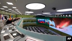 FILE - Russian President Vladimir Putin, fifth left, and other top officials oversee the test launch of the Avangard hypersonic missile from the Defense Ministry's control room in Moscow, Dec. 26, 2018. 