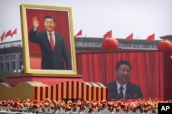 FILE - Participants cheer beneath a large portrait of Chinese President Xi Jinping during a parade to commemorate the 70th anniversary of the founding of Communist China in Beijing, Oct. 1, 2019.