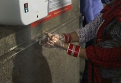 A woman sanitizes her hand at Delhi Metro station before boarding the train in Gurugram on the outskirts of New Delhi, India, Sept. 7, 2020.