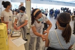 A health worker is inoculated with a COVID vaccine at the Clinicas Hospital in Sao Paulo, Brazil, Jan. 18, 2021.