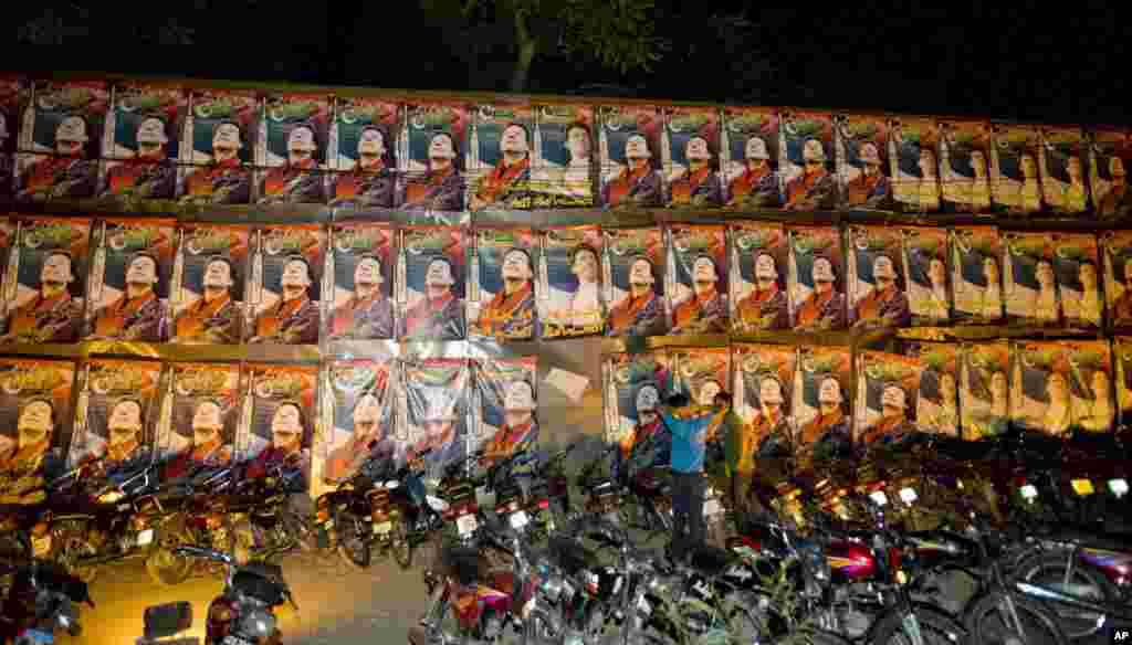 Supporters of former cricket star-turned-politician, and leader of Pakistan Tehreek-e-Insaf party, Imran Khan stand beside a wall covered with posters of Khan at a PTI office in Lahore, May 11, 2013.