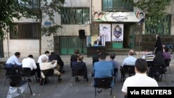 People watch the debate of presidential candidates on a street in Tehran, Iran, June 8, 2021. (Majid Asgaripour/WANA (West Asia News Agency) via Reuters) 