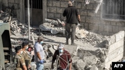 Lebanese army soldiers stand by as people clear debris and rubble from the site of a previous Israeli airstrike on the village of Aito in northern Lebanon, Oct. 15, 2024.